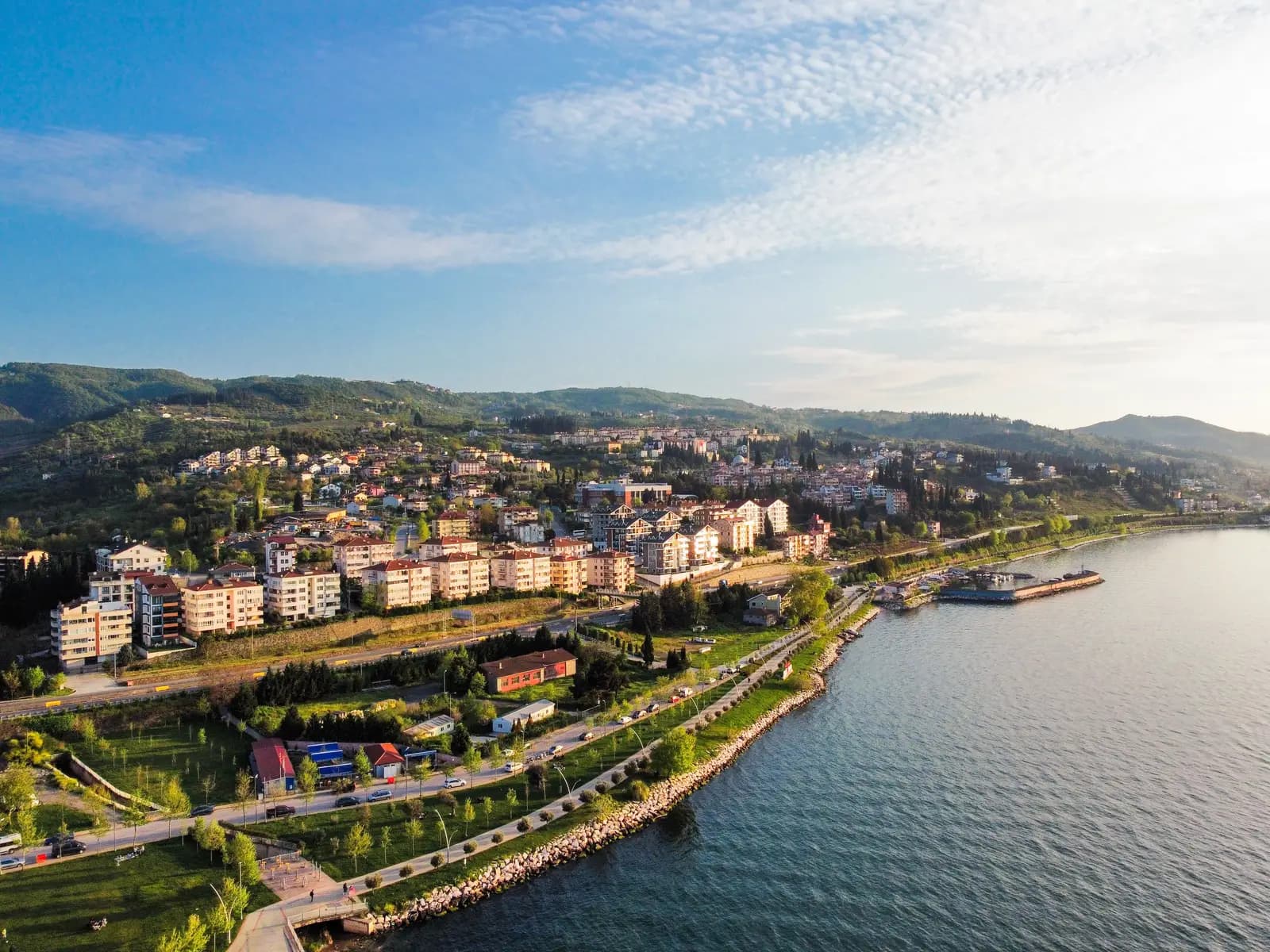 Aerial view at sunset of a Marmara coastal town surrounded by green hills