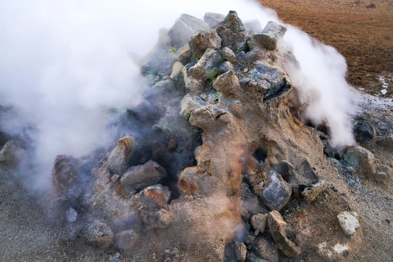 Dense thermal steam rising from a stone-textured rock formation